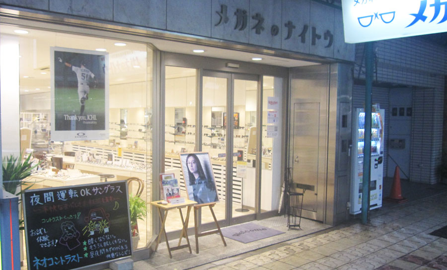 メガネ店「メガネのナイトウ」の外観。店の入り口には眼鏡の展示や看板があり、夜間営業を示すポスターが掲示されている。